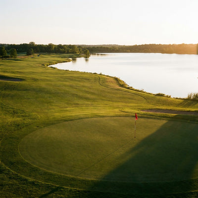 Golf wall art showing a golf course fairway with a lake and a putting green at golden hour