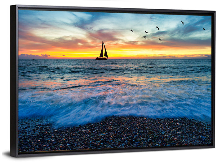 Sunset Sailboat Over Pebble Shore Wall Art as a framed canvas