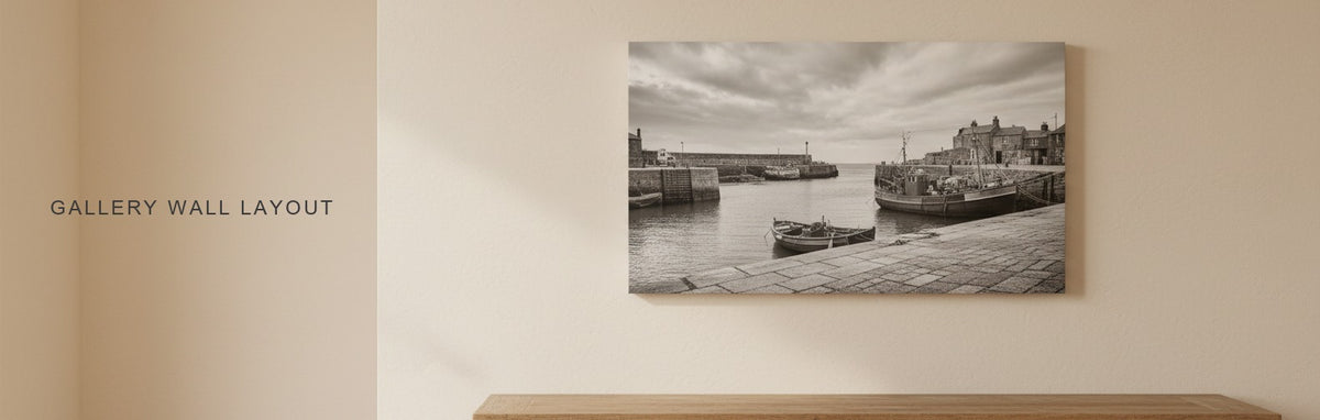 Gallery wall layout in a hallway above a long console: separate black and white prints of an old harbor with even spacing