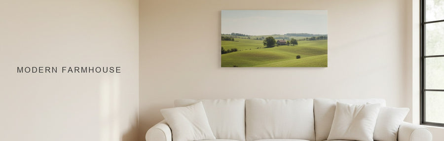 Modern farmhouse living room with black window frames and a slipcovered sofa under a canvas of green country hills