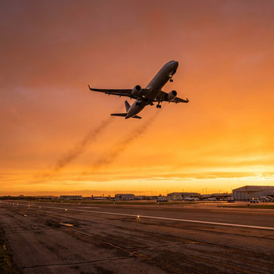 Aviation wall art: a passenger airliner climbing into a sunset sky above an airport runway
