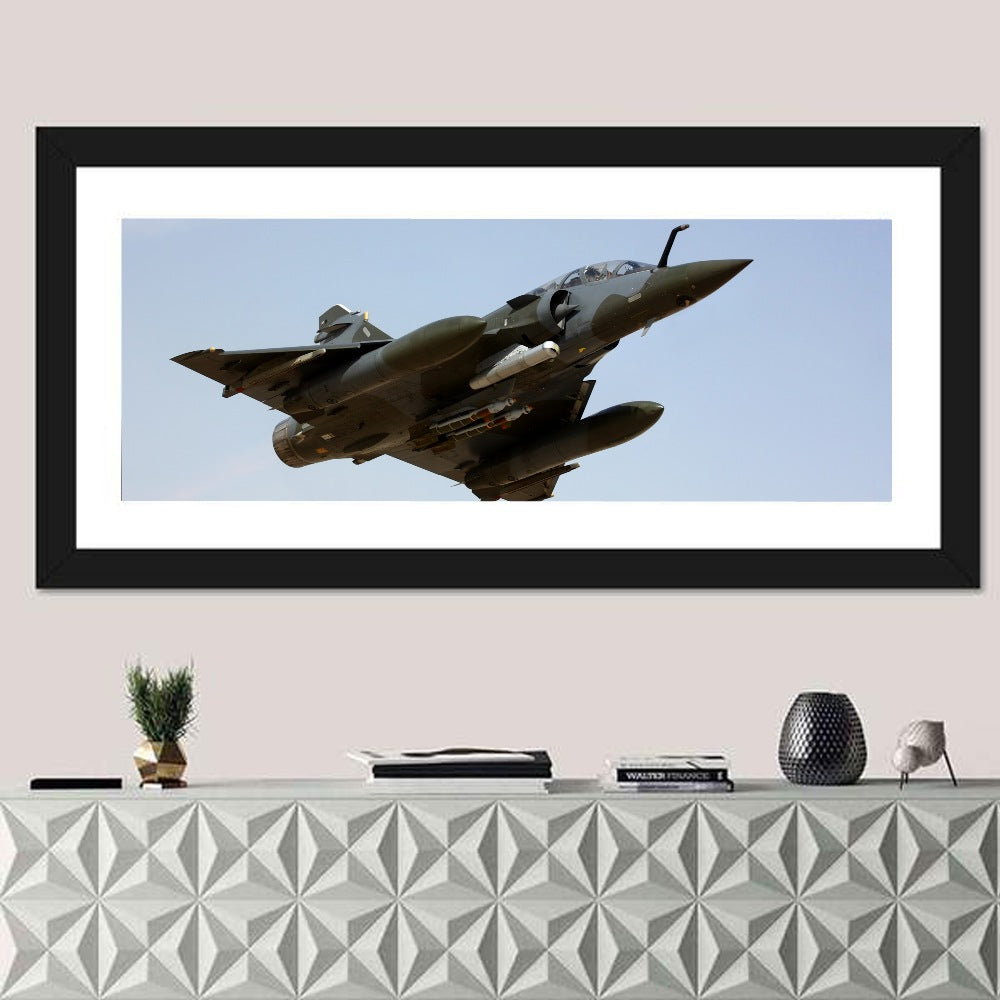 Camouflaged Fighter Jet in Flight Wall Art in a room, panoramic