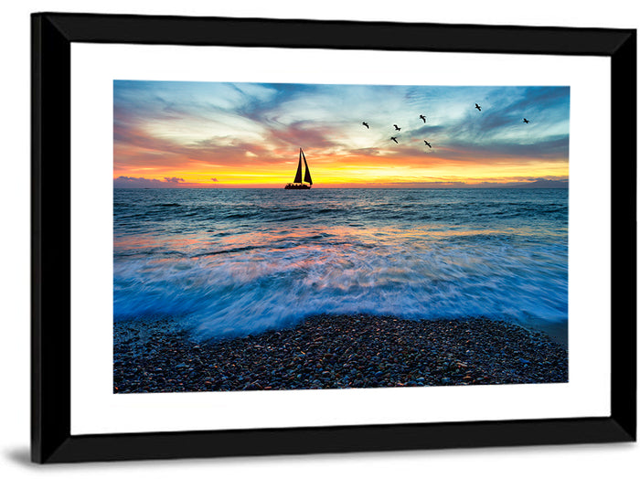 Sunset Sailboat Over Pebble Shore Wall Art as a framed print